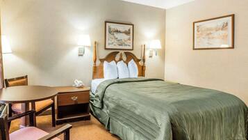 A hotel room with a bed, a desk, a chair, and two wall-mounted lamps.