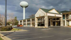 A motel with a large water tower in the background, a covered parking area, and a two-story building with a green roof. - Quality Inn Reidsville Hwy 29 (Reidsville)