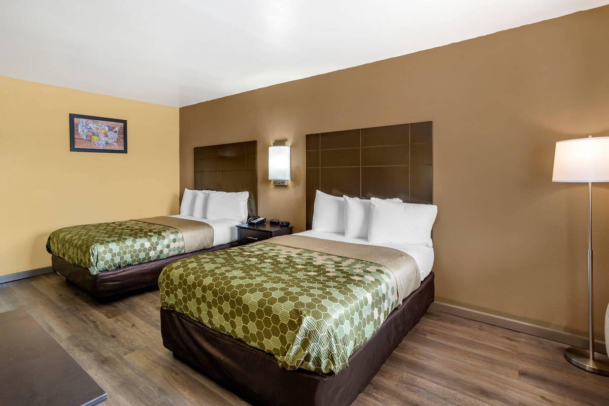 Ein Hotelzimmer mit zwei Betten, einem Nachttisch, einer Lampe und einer Wandleuchte.