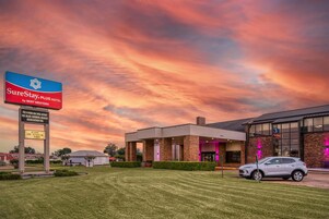 A hotel with a large sign advertising SureStay Plus Hotel by Best Western, featuring amenities like high-speed internet, continental breakfast, and an indoor/outdoor pool.