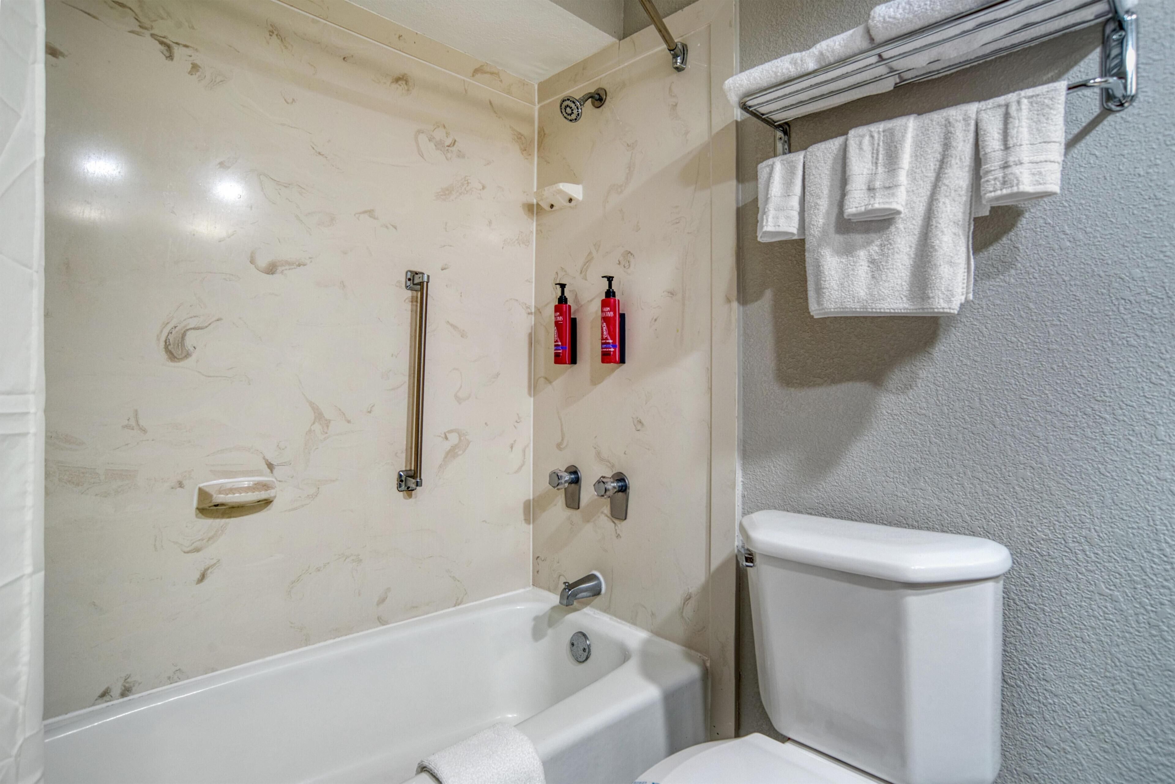 Um banheiro com banheira, vaso sanitário e porta-toalhas com toalhas.