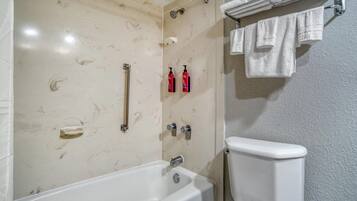 Um banheiro com banheira, vaso sanitário e porta-toalhas com toalhas.