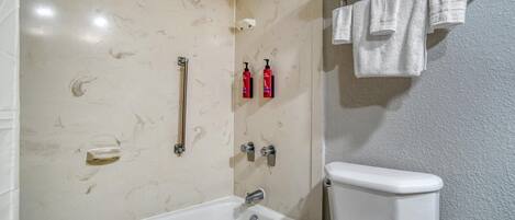 Un baño con bañera, inodoro y toallero con toallas.