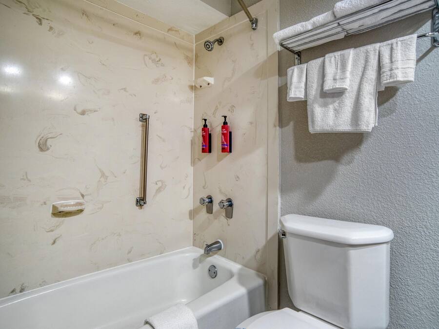 Um banheiro com banheira, vaso sanitário e porta-toalhas com toalhas.