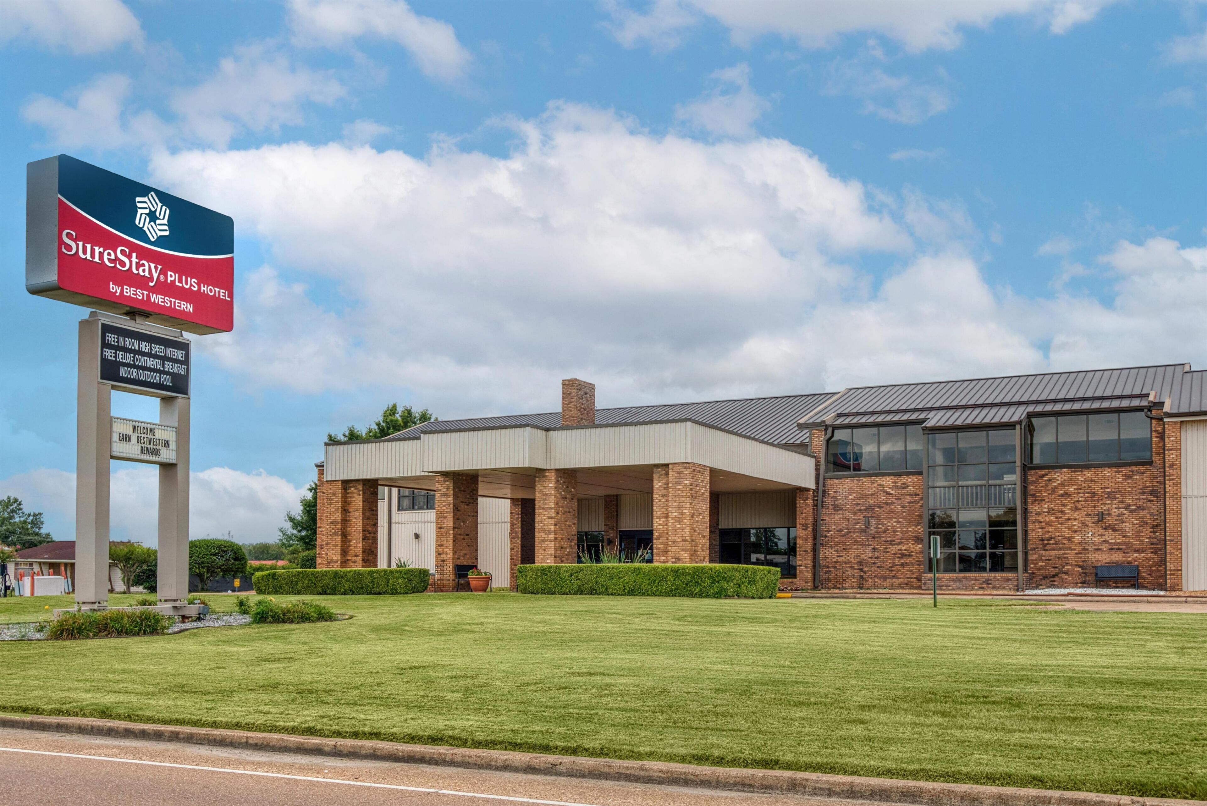 A hotel with a large signboard, a covered outdoor area, and a brick building.