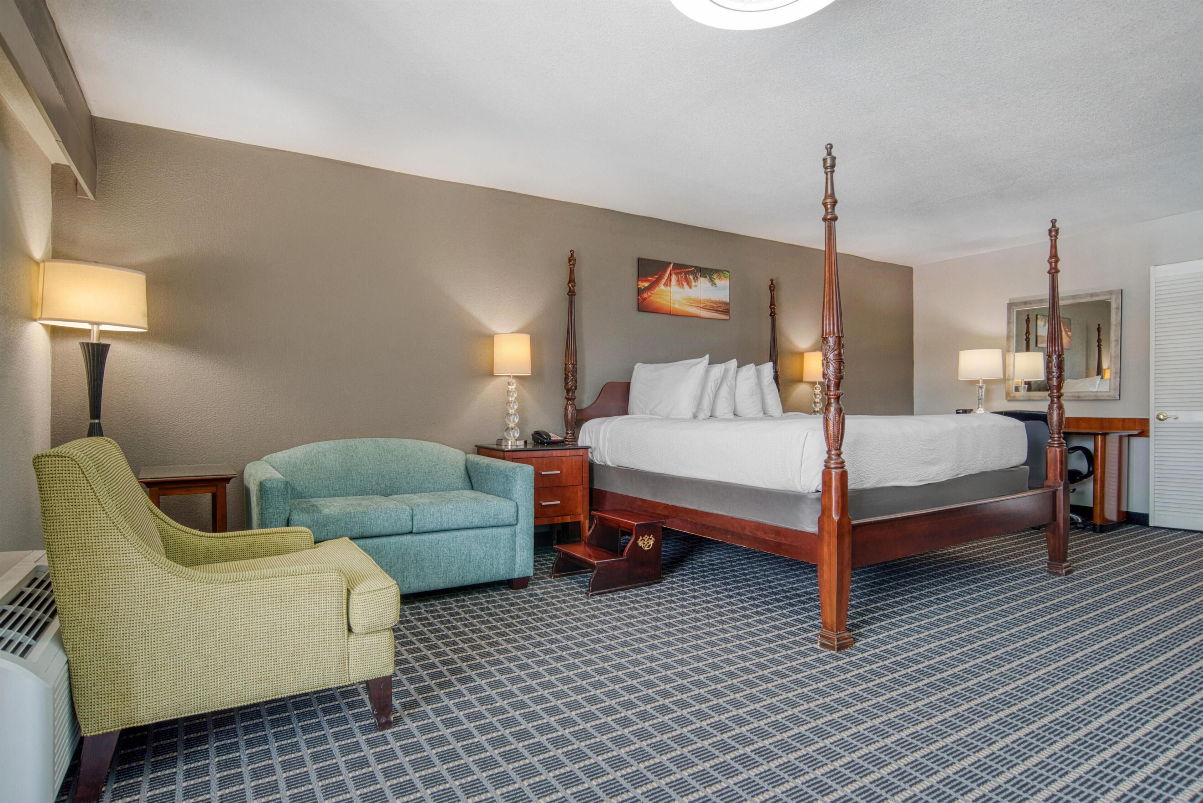 Ein Hotelzimmer mit Himmelbett, einem Sessel, einem Schreibtisch und einem Nachttisch.