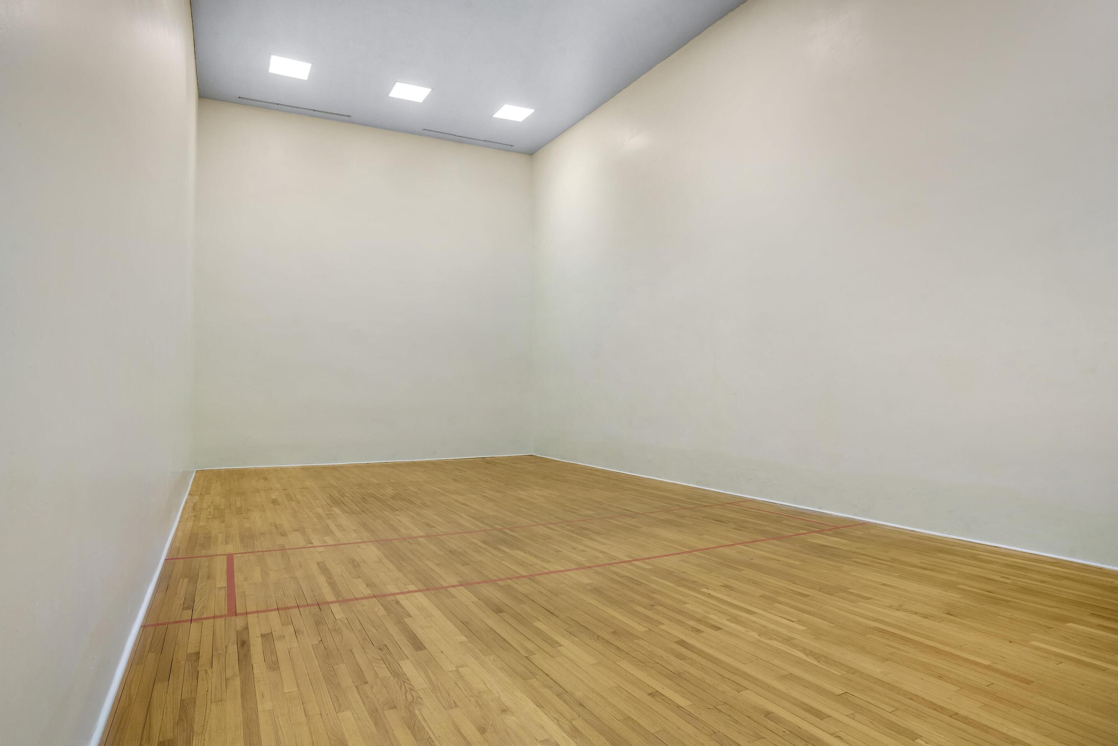 Una habitación con suelo de madera, paredes blancas e iluminación empotrada en el techo.