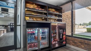 Un intérieur moderne avec un distributeur automatique, un présentoir réfrigéré et une vue sur l’extérieur par une fenêtre.