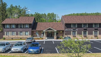 Un hôtel à la façade en briques, doté d’un parking et d’une pelouse verdoyante.