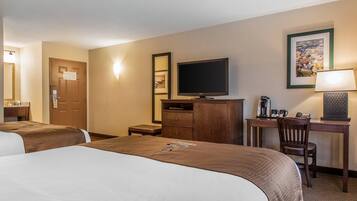 A hotel room with two beds, a desk with a computer, a television, and a coffee maker.