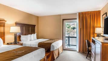 Habitación de hotel con dos camas, un escritorio, una silla, un televisor y un balcón con cortinas.