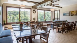 A dining area with large windows, wooden furniture, and a view of a lake. - The Black Swan Lee - Lenox, an Ascend Collection Hotel (Lee)