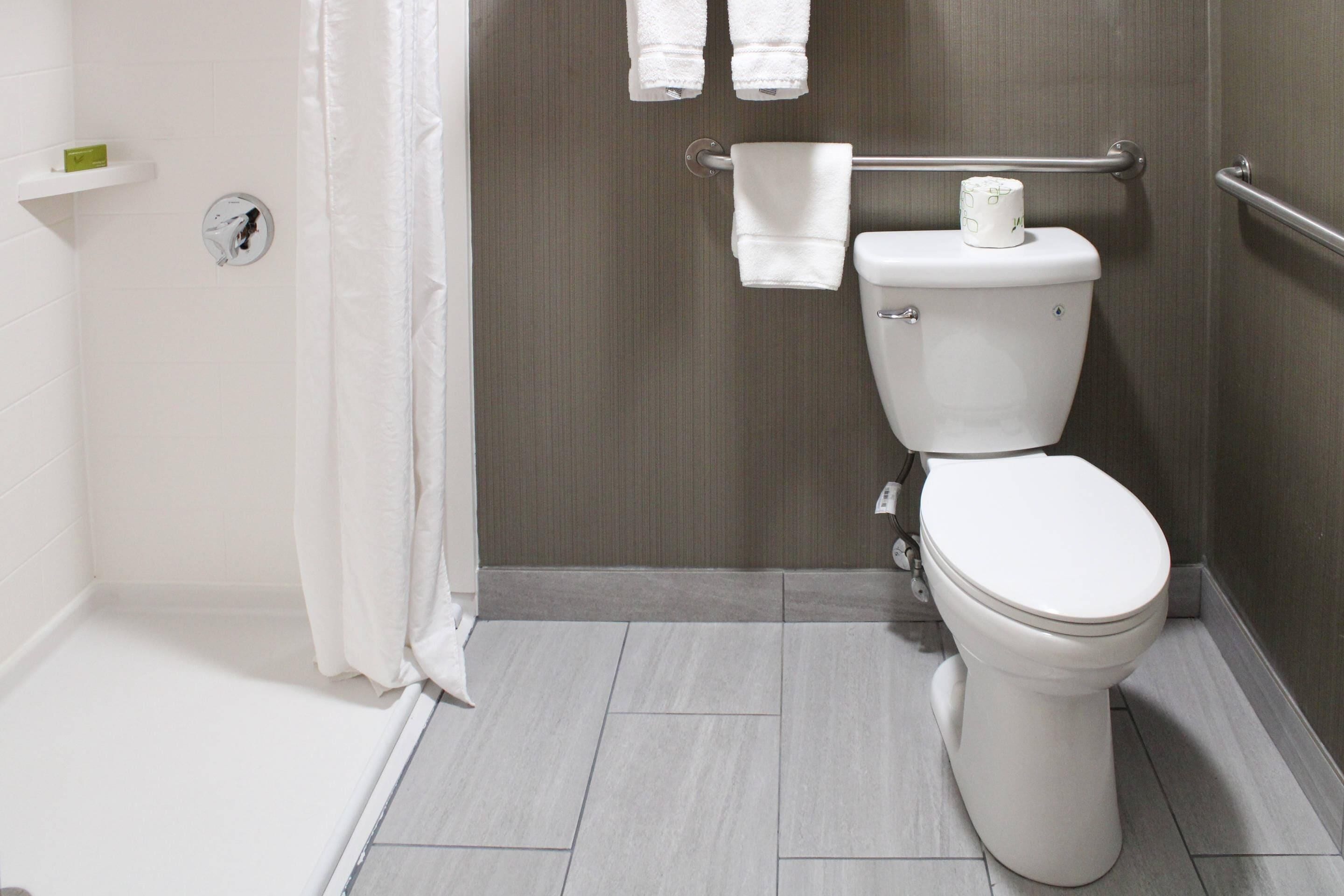 A modern bathroom with a white toilet, a shower area, and a towel rack.