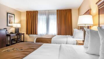 Ein Hotelzimmer mit zwei Betten, einem Schreibtisch, einem Stuhl und einer Lampe.