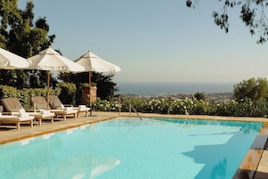 Una piscina al aire libre, sombrillas, tumbonas