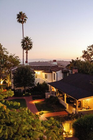 A residential property with a large patio area, a covered outdoor seating area, and a view of the surrounding landscape.