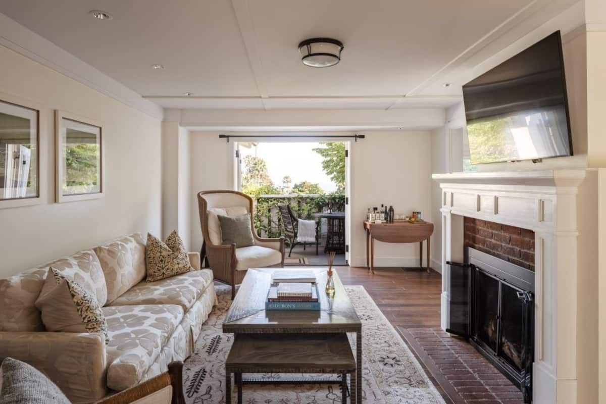A living room with a sofa, coffee table, fireplace, and a television mounted above it.