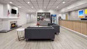 Un hall d’entrée spacieux avec une cheminée, des canapés, un comptoir de réception et un distributeur de boissons.