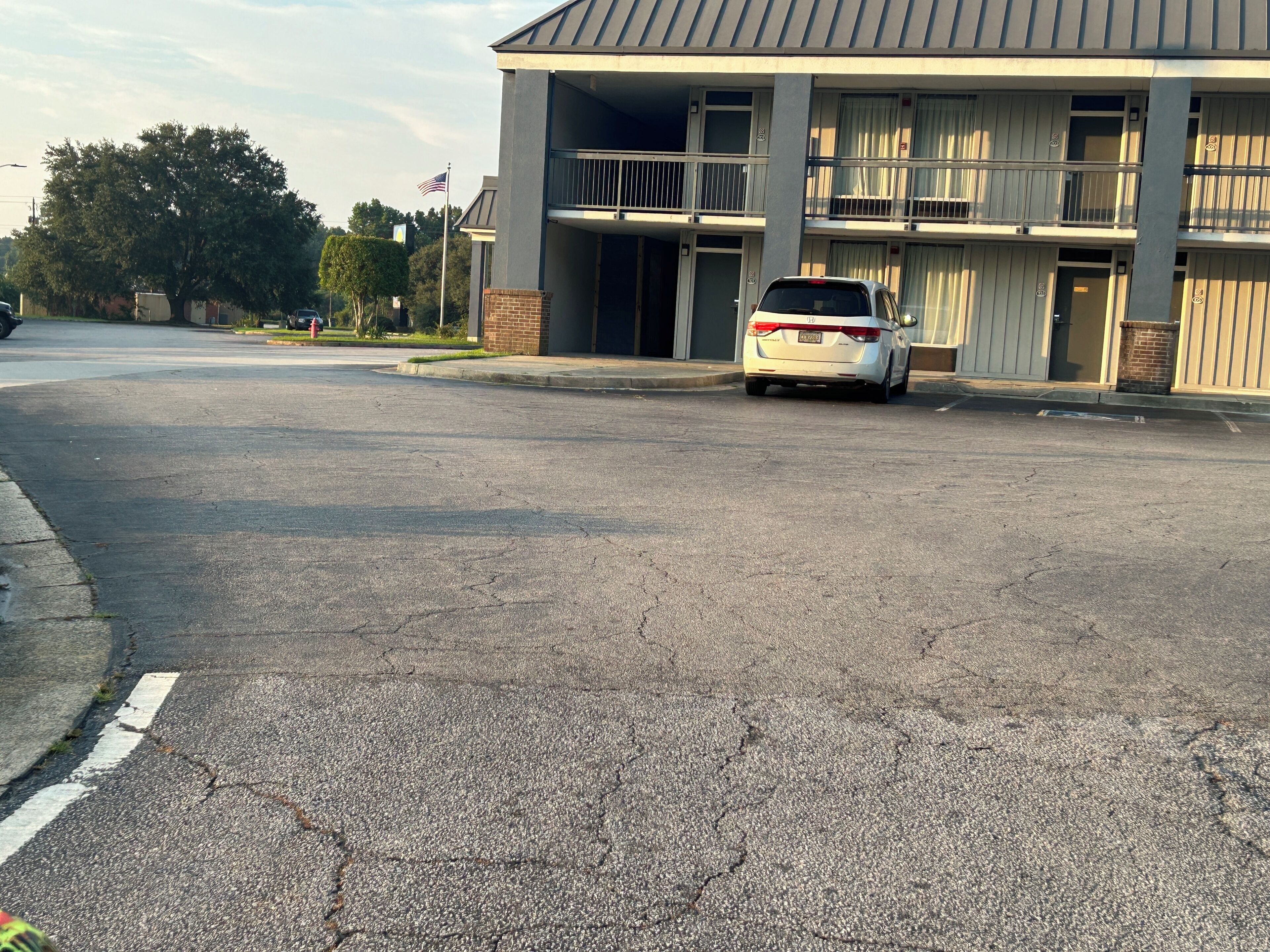 A building with a parking lot and a white car parked in front.