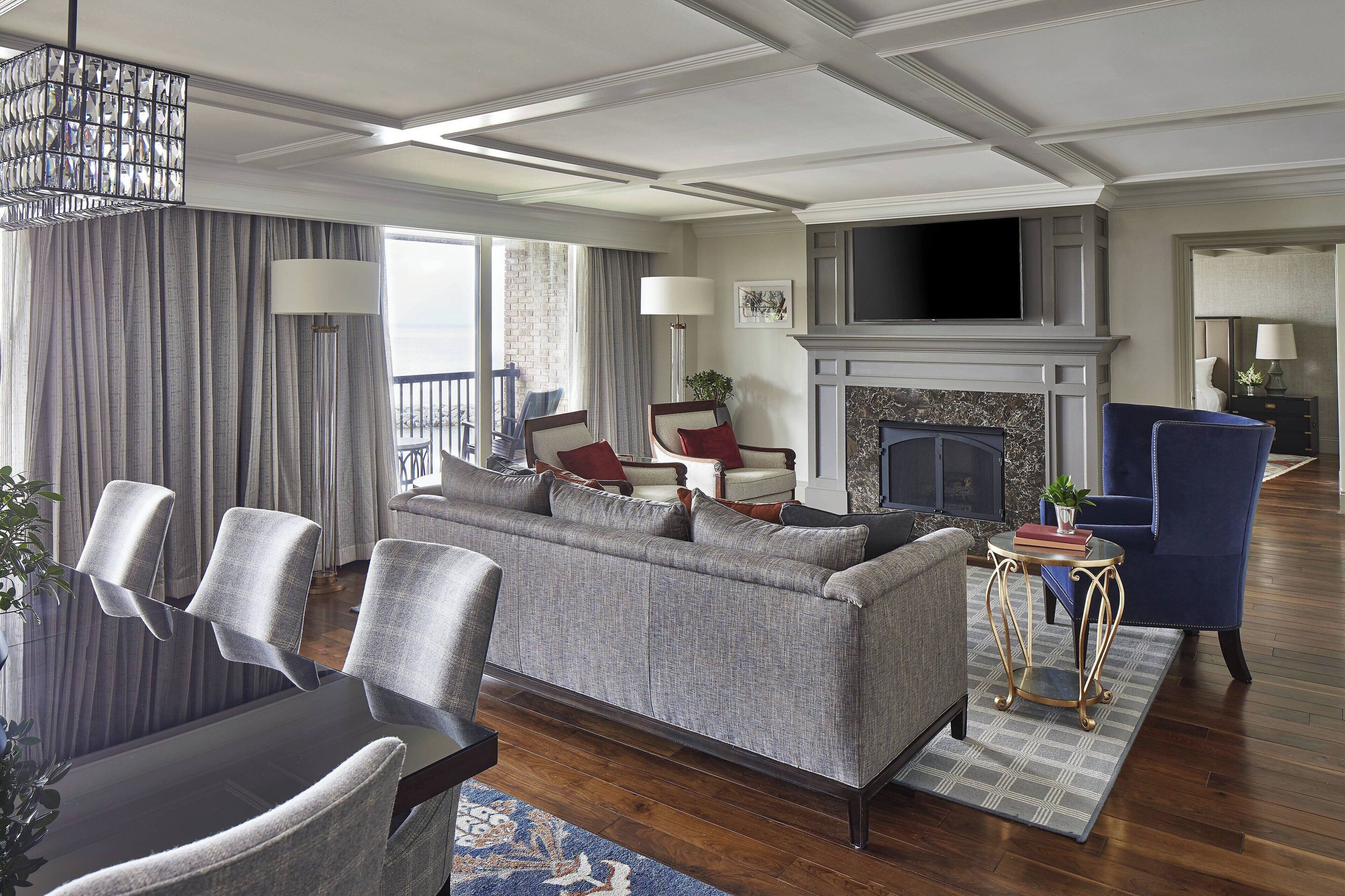A modern living room with a grey sofa, armchairs, a fireplace, and a television.
