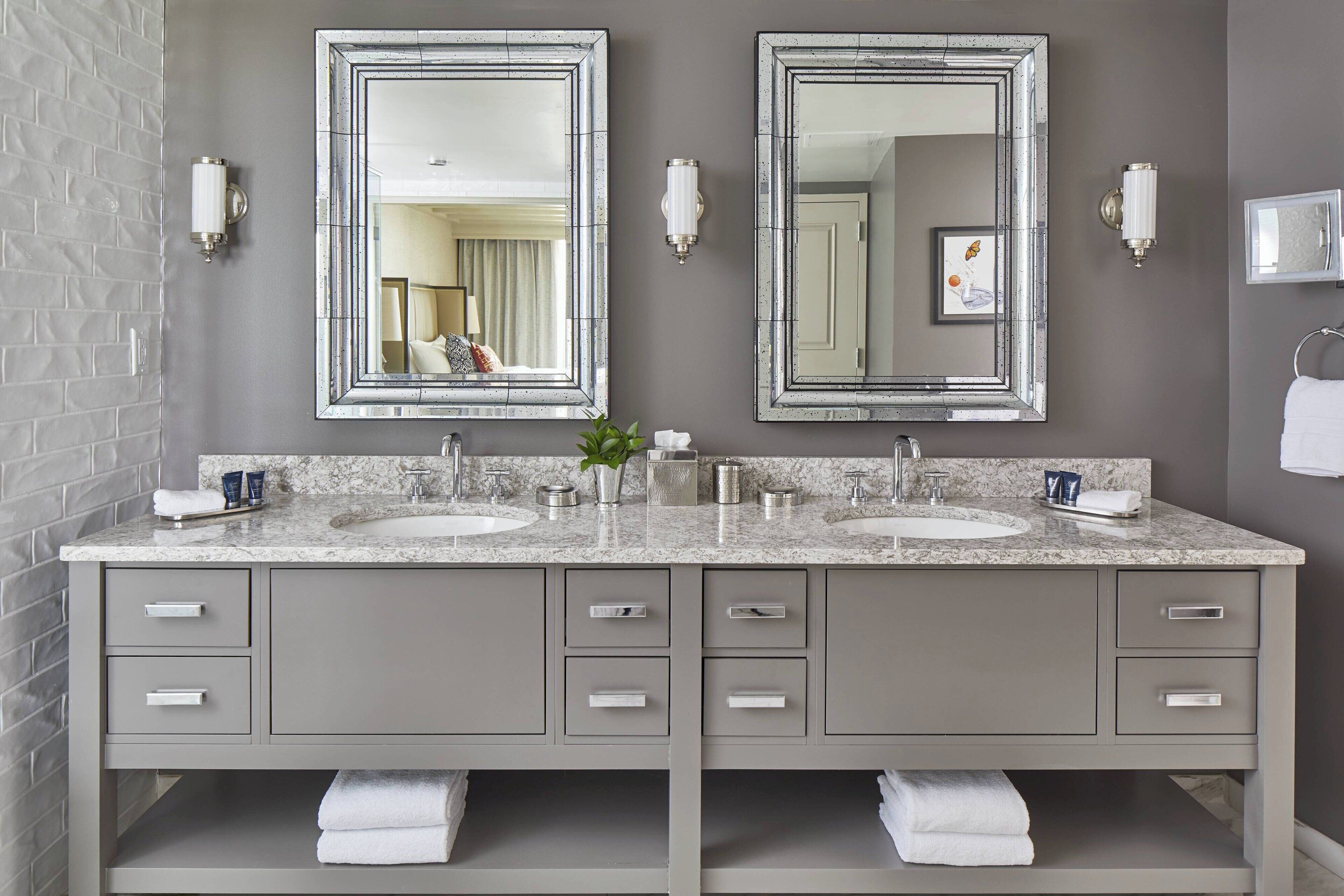 A bathroom with two sinks, a mirror, and a towel rack.