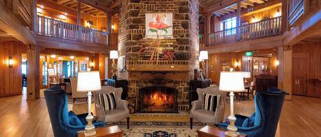Eine geräumige Lobby mit Kamin aus Stein, Holzböden und hoher Decke.
