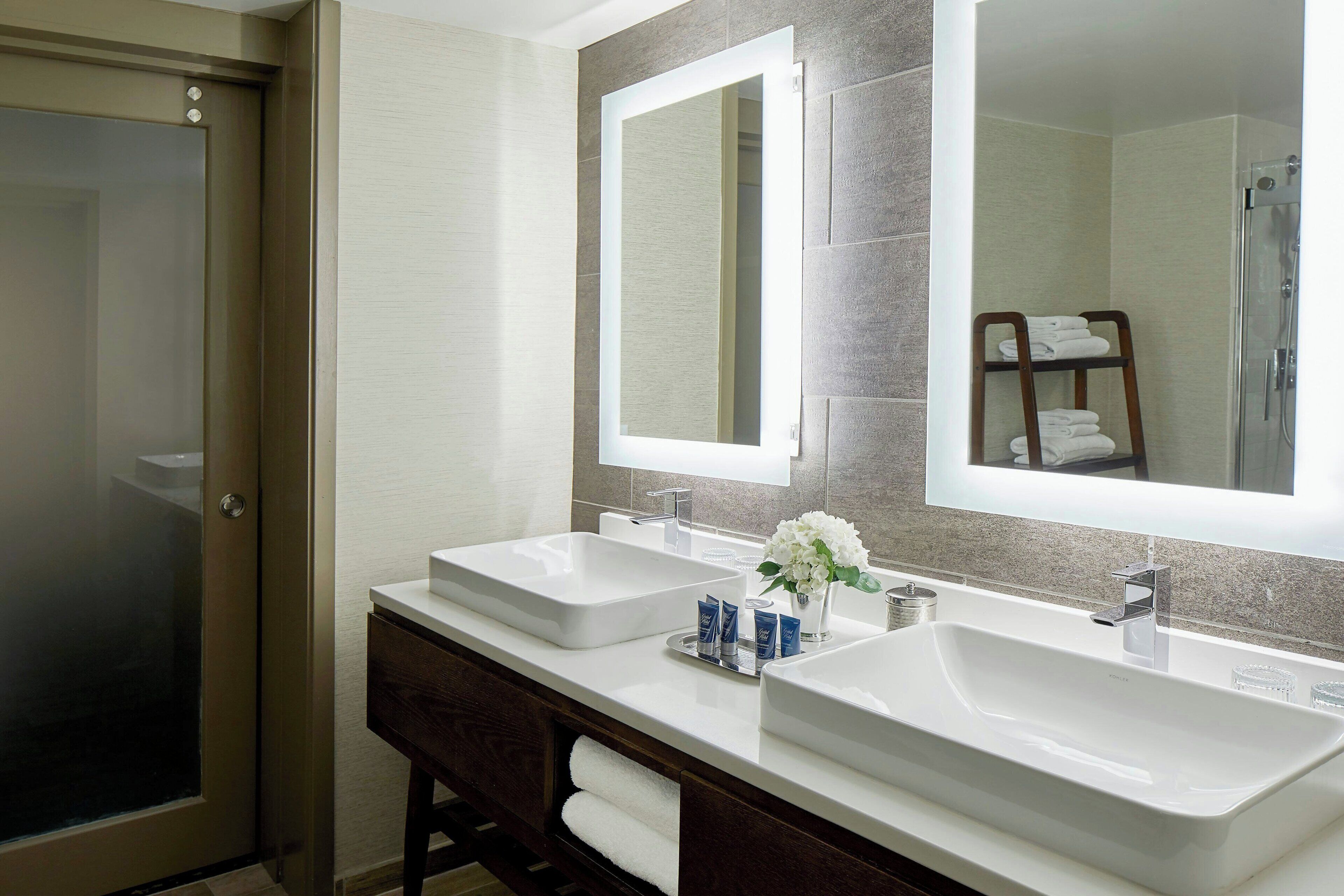 A bathroom with two sinks, a mirror, and a shower.