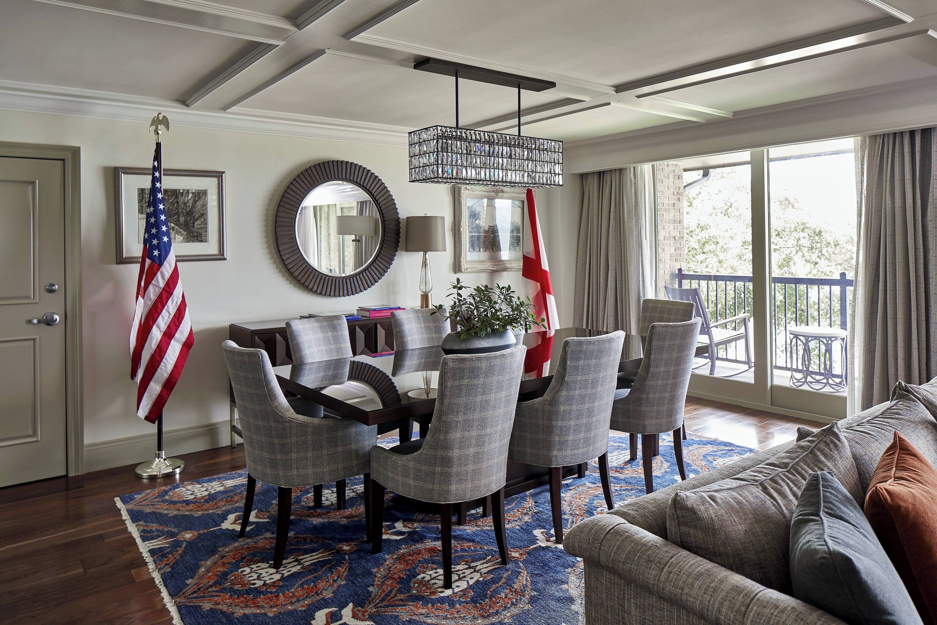 A dining area with a chandelier, a flag, and a view to the outside.