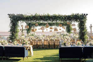 An outdoor wedding setup with tables, chairs, and a decorative archway.