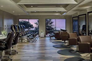 A modern spa with multiple massage chairs, a reception area, and large windows offering a view of the outdoors.