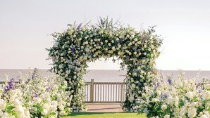 A wedding arch with floral arrangements, a grassy pathway, and a view of the sea. - Grand Hotel Golf Resort & Spa, Autograph Collection (Fairhope)