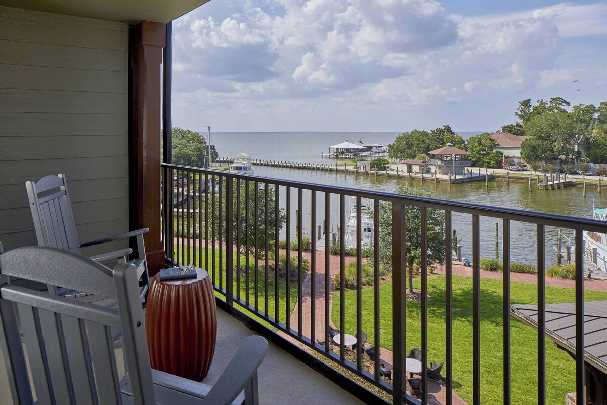 A balcony with a view of a marina, a chair, and a decorative vase.