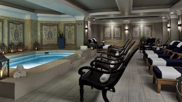 Relax by the central pool surrounded by lounge chairs and benches, amidst intricate tile work and ambient lighting.