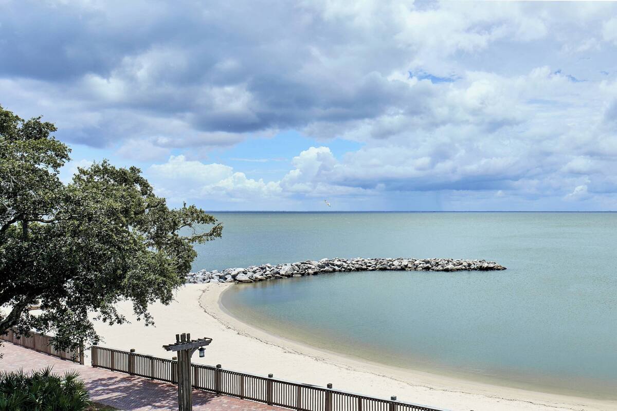 Une plage avec une promenade en bois et une digue rocheuse.