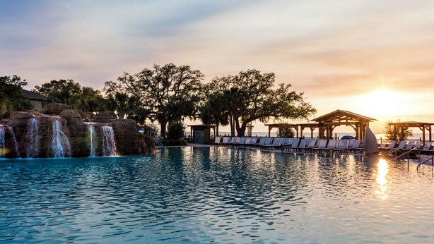 A pool with a waterfall, lounge chairs, and a gazebo. - Grand Hotel Golf Resort & Spa, Autograph Collection (Fairhope)