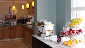Een ontbijtbuffet met diverse soorten fruit, een repenstaaf van Hershey's chocolade en een koffieapparaat.