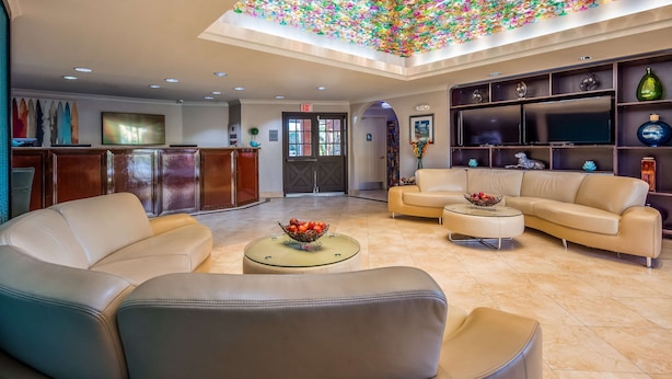 Een ruime lobby met leren banken, een ronde salontafel met fruit, en een plafond versierd met kleurrijke hangdecoraties.