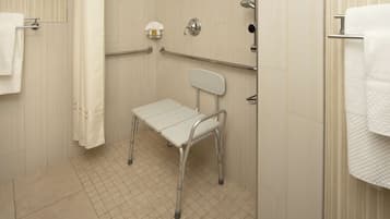 A bathroom with a white tiled floor, a white shower curtain, a white towel rack, a white toilet, and a white grab bar.