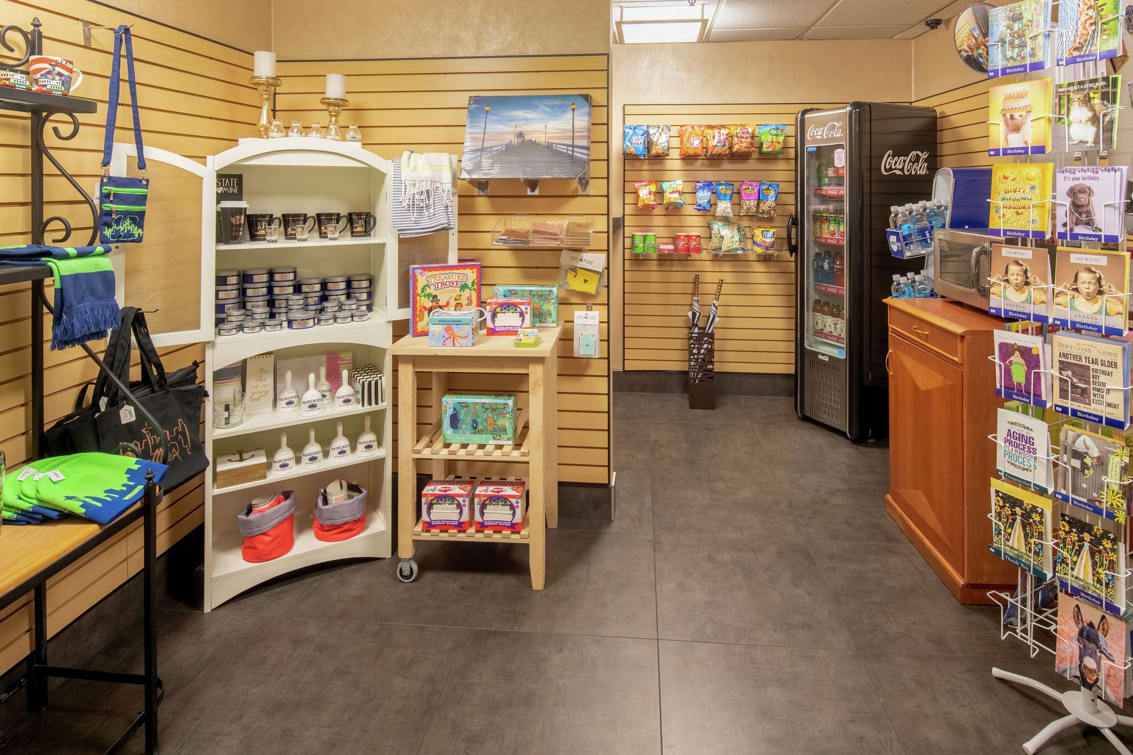 A store with shelves of various products, a refrigerator, and a display of greeting cards.