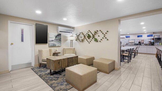 A modern living room with a sofa, ottomans, and a coffee table. There is a dining area with chairs and a table. - Best Western El Rancho Palacio (Roswell)