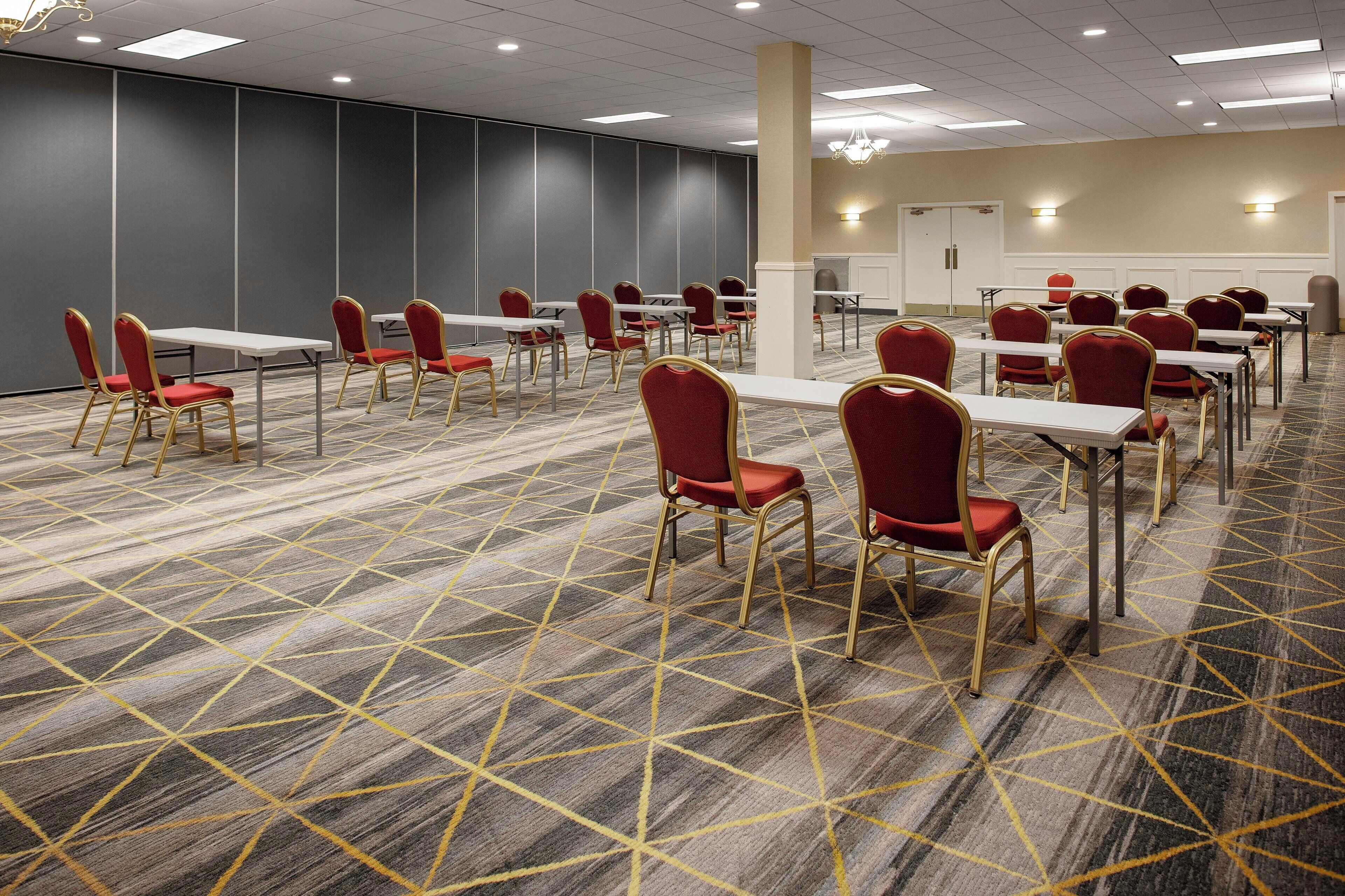 A conference room with rows of tables and chairs, a patterned carpet, and a modern ceiling design.