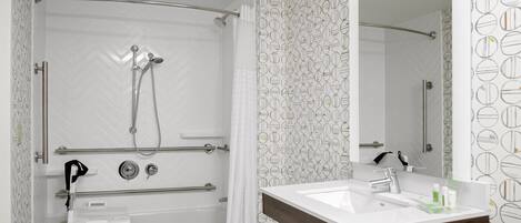 Une salle de bain moderne avec une douche, un meuble-lavabo avec un miroir et un mur décoré d’un motif.