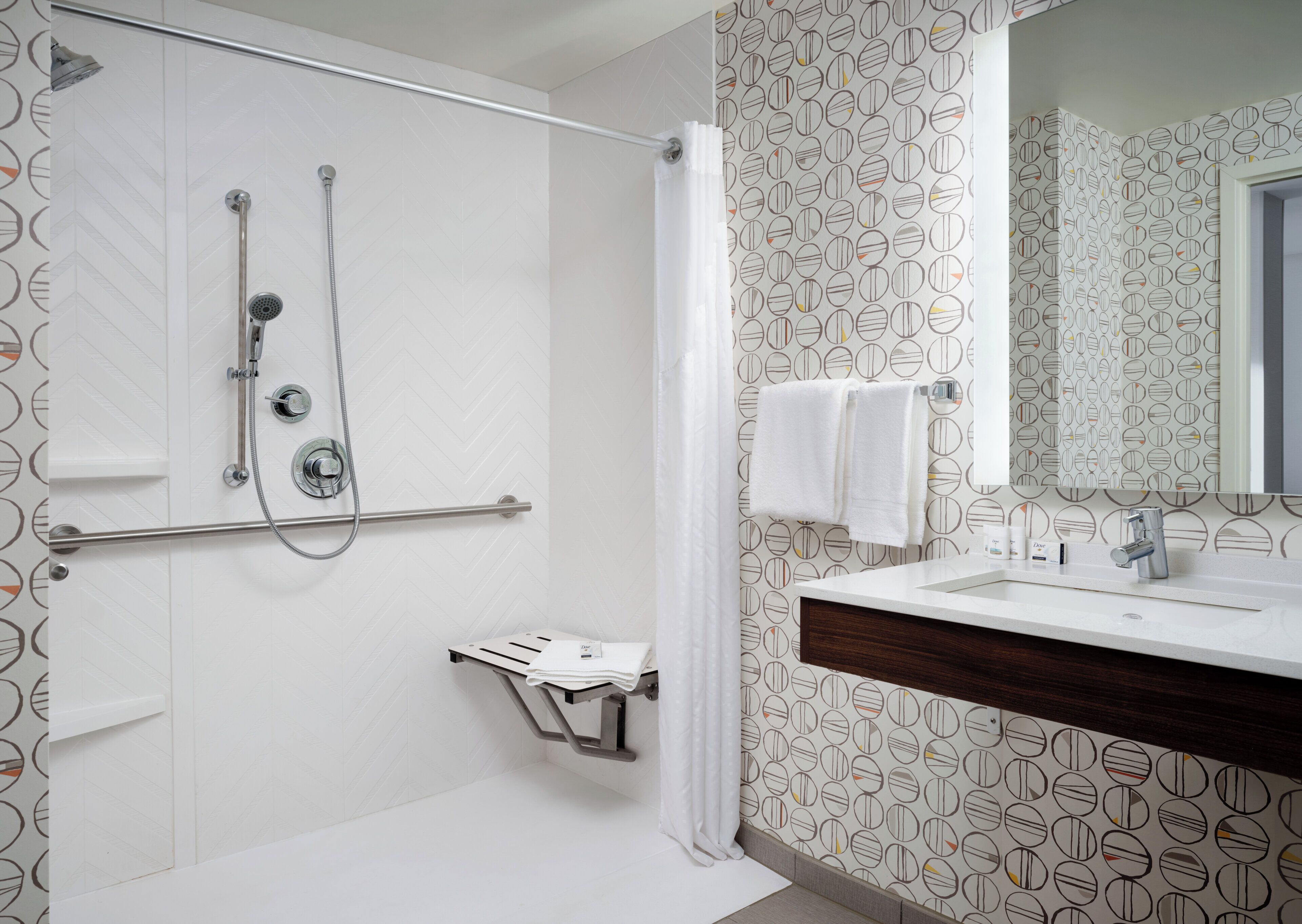 Un bagno moderno con doccia, un lavabo con specchio e carta da parati decorata.