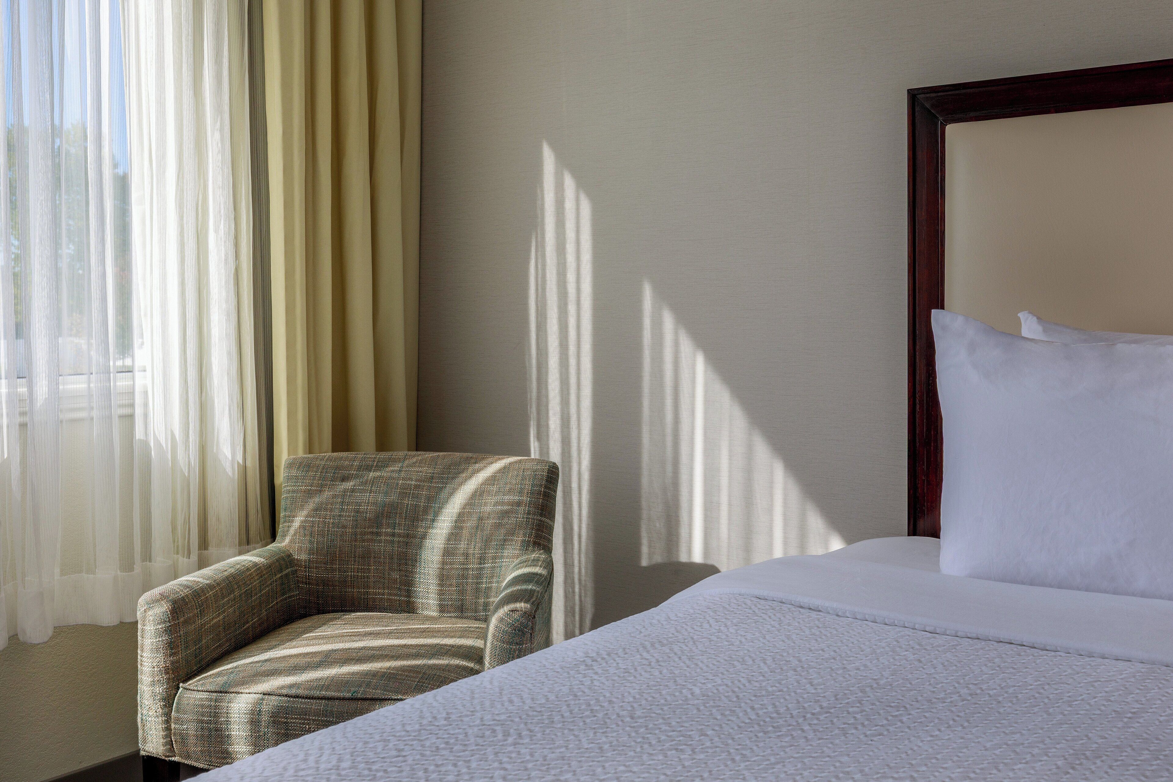 Ein Hotelzimmer mit einem Bett, einem Sessel und transparenten Vorhängen.
