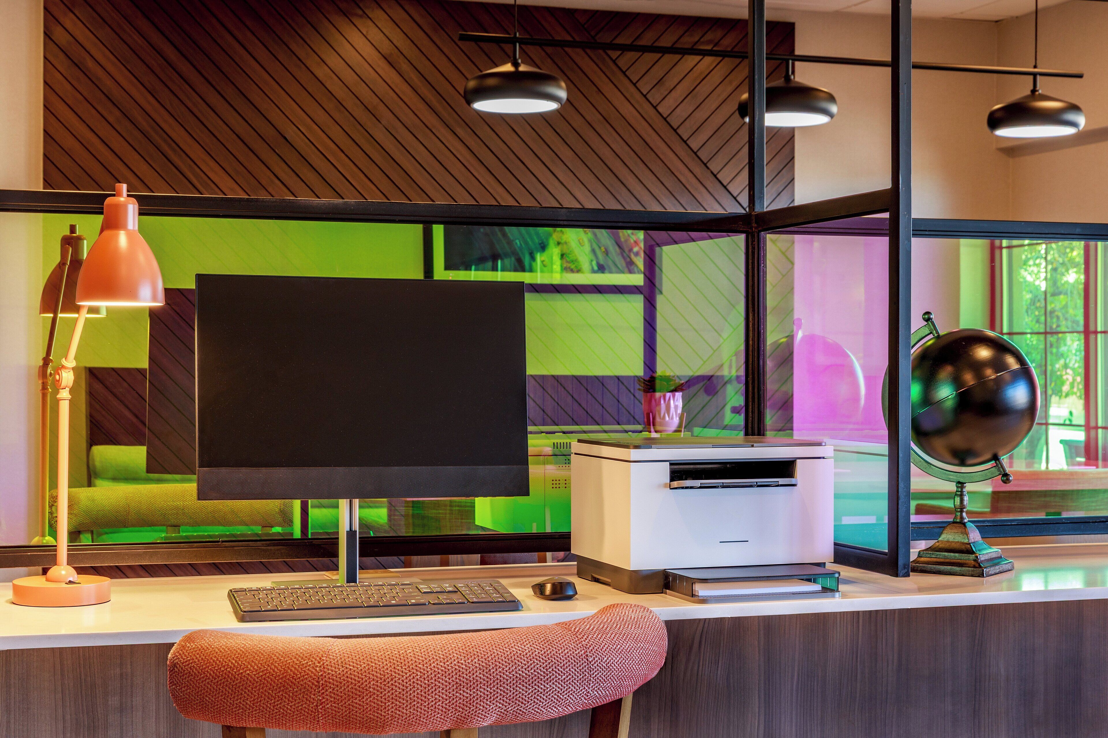 A modern office desk with a computer, keyboard, and lamp.