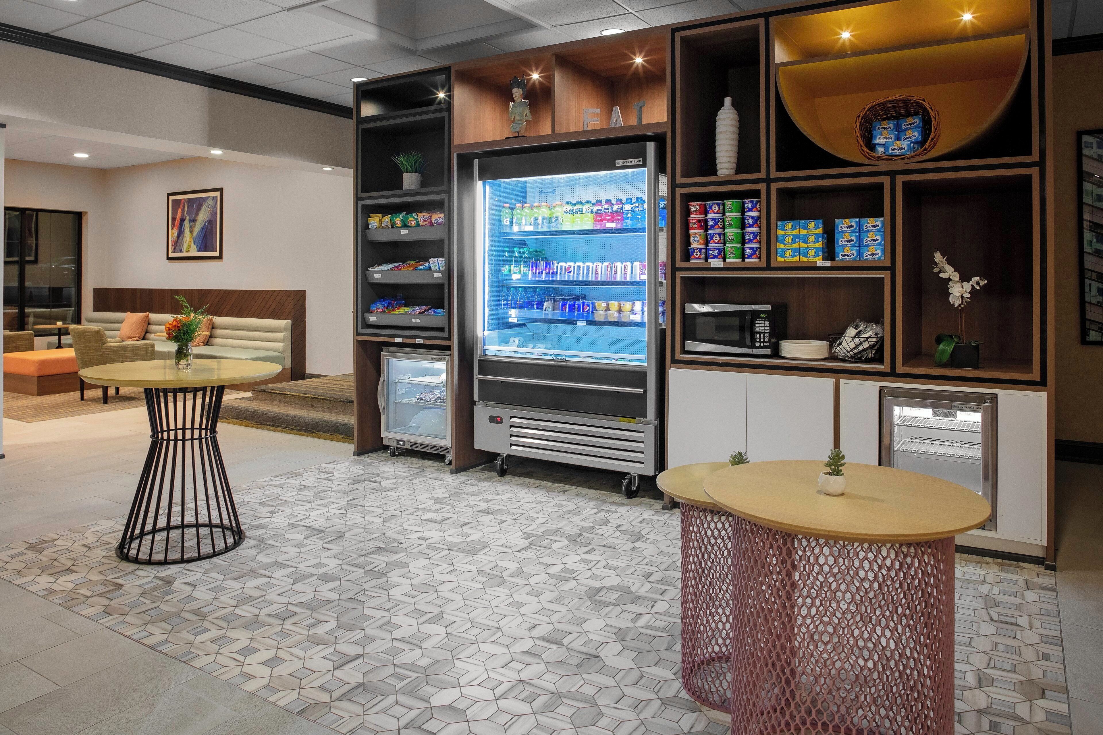 A modern interior with a refrigerated display, seating area, and vending machines.