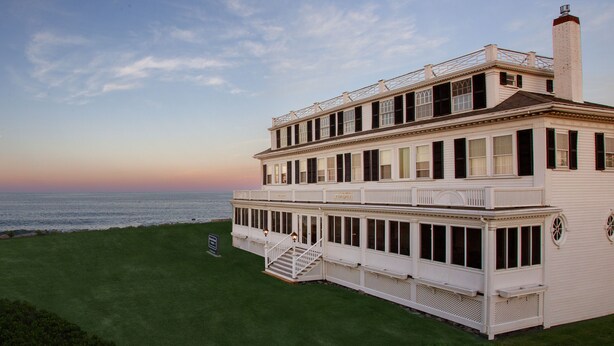 A large, white, two-story building with a balcony and a staircase leading to a lower level. - Ocean House Hotel at Bass Rocks (Gloucester)