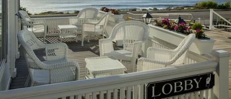 Una terraza con mobiliario de mimbre blanco y un cartel que dice 'Lobby'.