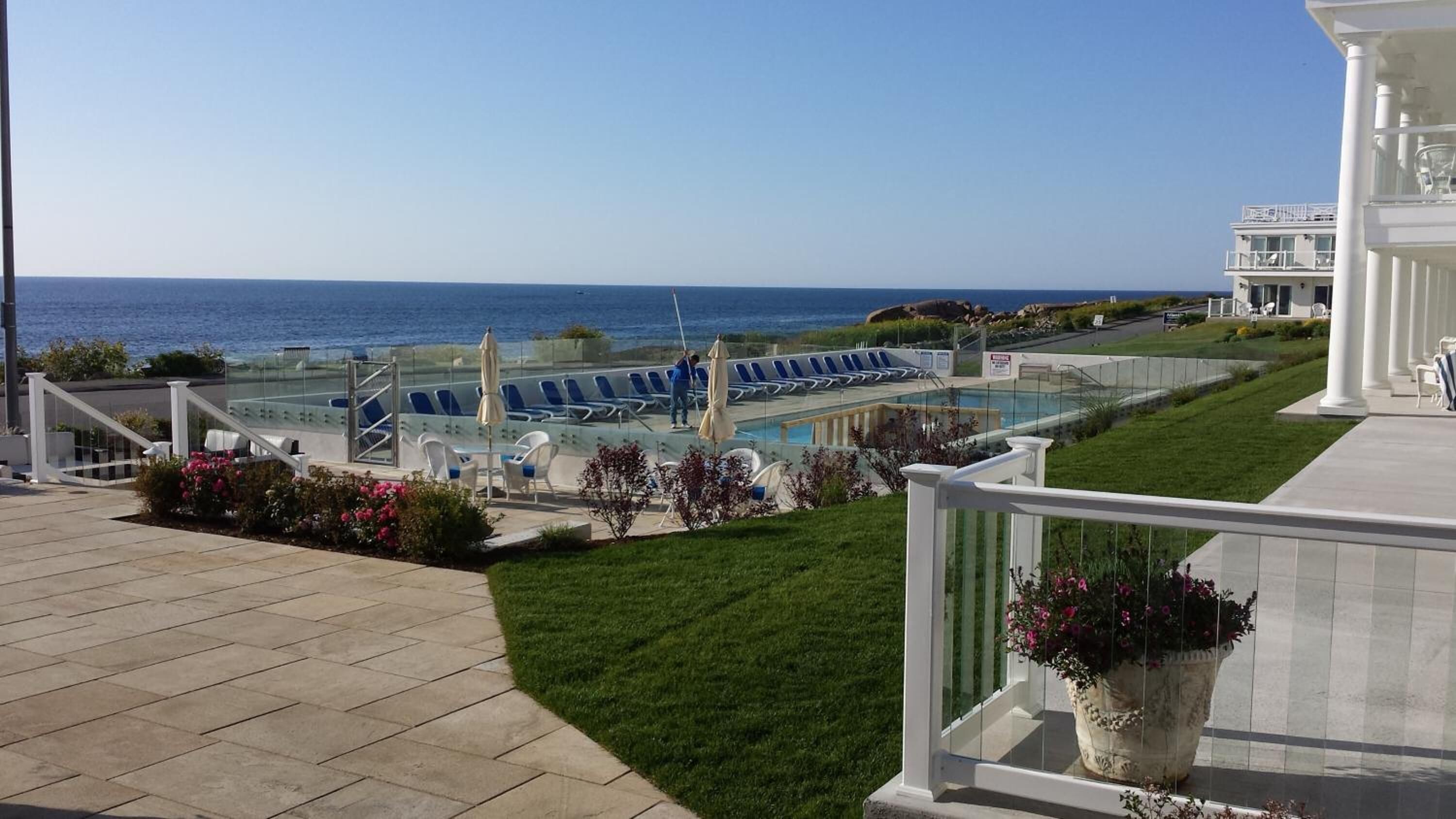 A pool area with lounge chairs and a view of the ocean.