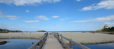 A wooden boardwalk leading to a beach with a clear sky.